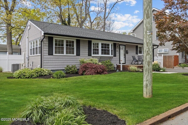 view of front of house with central AC, a front yard, roof with shingles, and fence