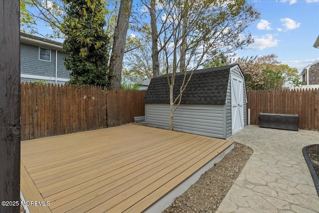 wooden deck featuring a storage shed, an outbuilding, and a fenced backyard