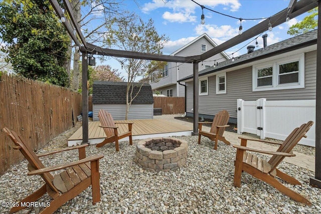 view of patio with a fenced backyard, a storage shed, a fire pit, and an outdoor structure