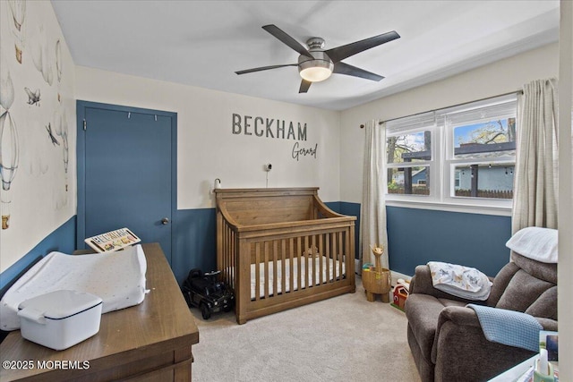 carpeted bedroom featuring a nursery area, a ceiling fan, and a closet