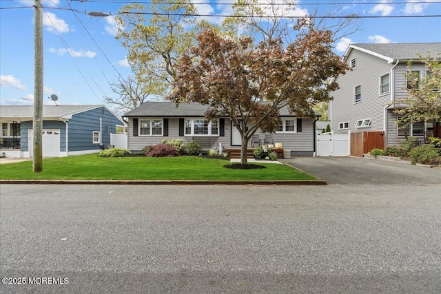 view of front of property featuring a front lawn, fence, and aphalt driveway