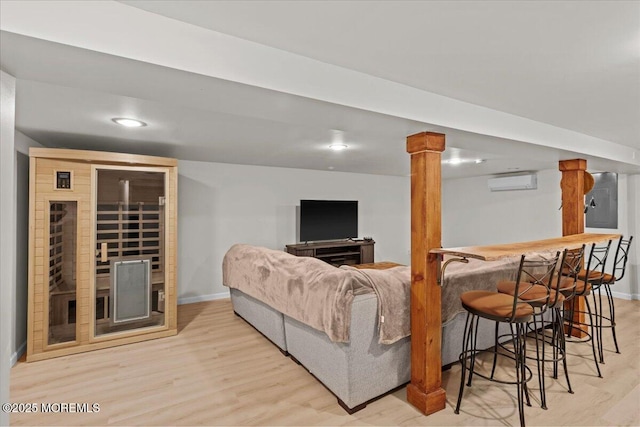 living room with baseboards, light wood-type flooring, and a wall mounted AC