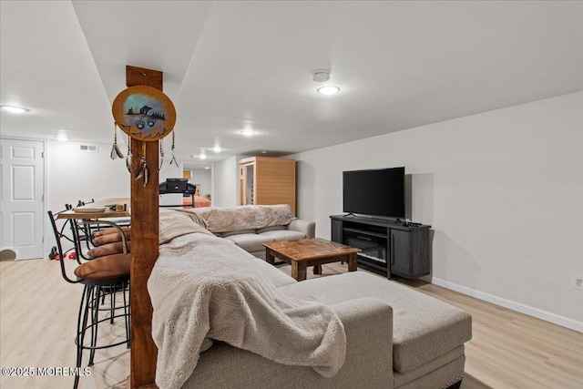 living room featuring baseboards, light wood-type flooring, and visible vents