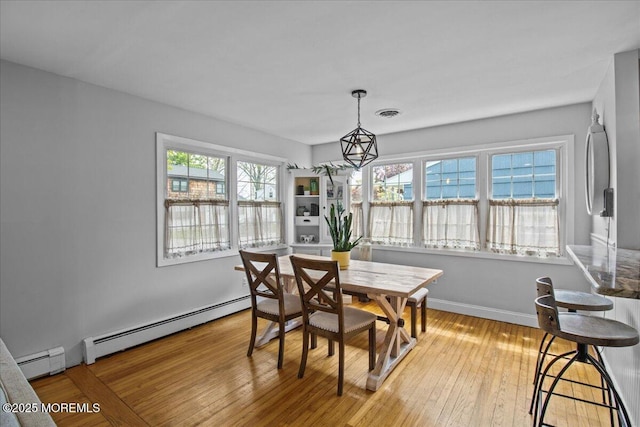 dining room with baseboards, a baseboard radiator, and light wood-type flooring