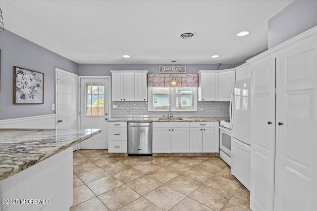 kitchen with white appliances, decorative backsplash, white cabinets, and a sink