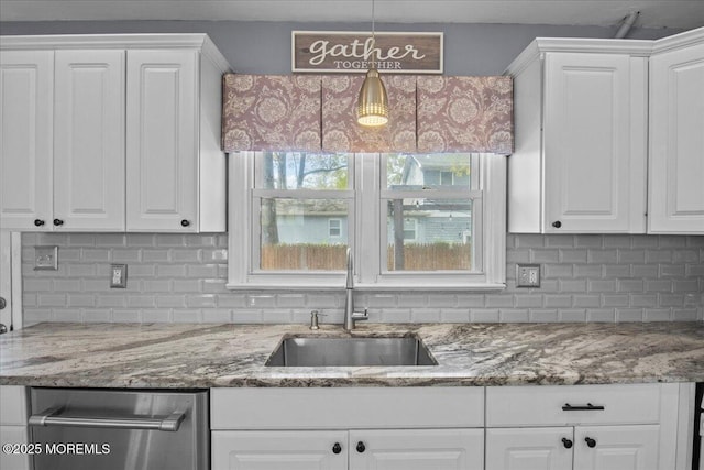 kitchen featuring a sink, pendant lighting, decorative backsplash, white cabinets, and light stone countertops