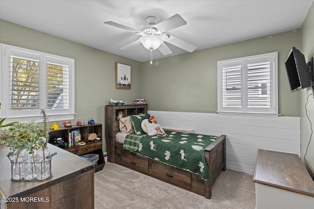 bedroom with ceiling fan, carpet floors, and a wainscoted wall