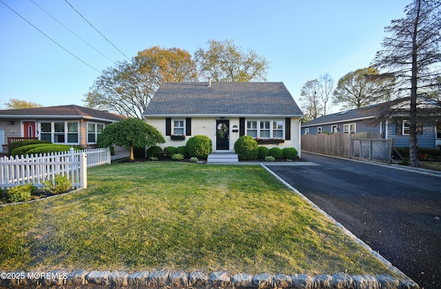 bungalow-style house with a front yard, aphalt driveway, and fence