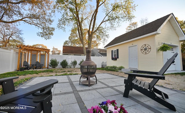 view of patio / terrace with an outdoor fire pit, an outbuilding, a pergola, and a fenced backyard