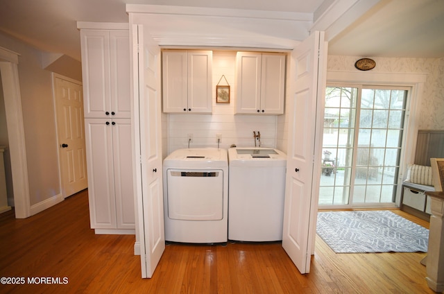 washroom with light wood-style flooring, cabinet space, and washer and dryer