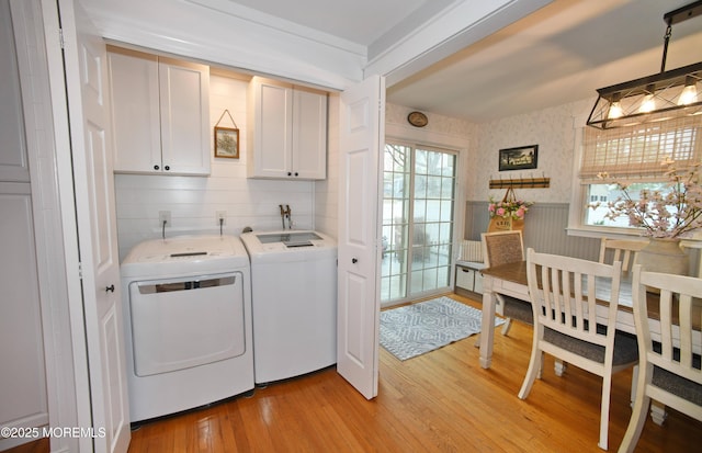 laundry room with light wood-style floors, plenty of natural light, washer and dryer, and cabinet space