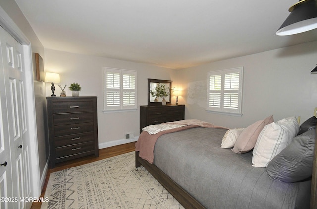 bedroom with baseboards, visible vents, and wood finished floors