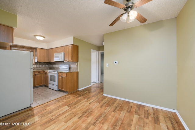 kitchen featuring white appliances, light wood finished floors, ceiling fan, decorative backsplash, and brown cabinets