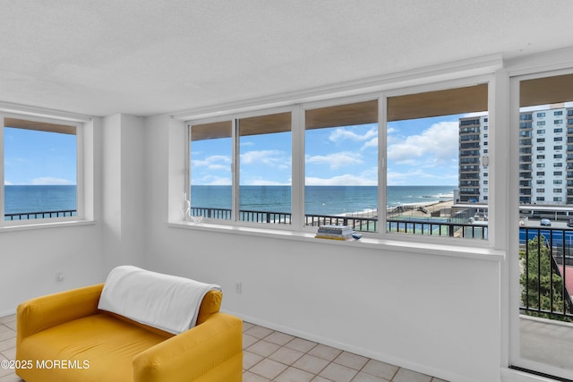 55 Ocean Ave Unit 3L, Monmouth Beach, NJ 07750 - sitting room with a water view, light tile patterned floors, healthy amount of natural light, a textured ceiling, and baseboards