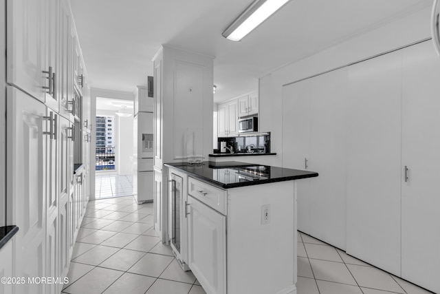 55 Ocean Ave Unit 3L, Monmouth Beach, NJ 07750 - kitchen featuring dark countertops, light tile patterned floors, white cabinetry, stainless steel microwave, and a kitchen island