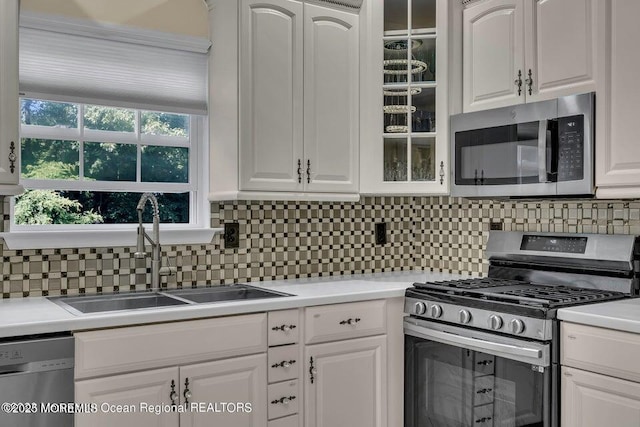 3688 Ridgeway Rd, Manchester, NJ 08759 - kitchen with appliances with stainless steel finishes, a sink, glass insert cabinets, backsplash, and white cabinetry