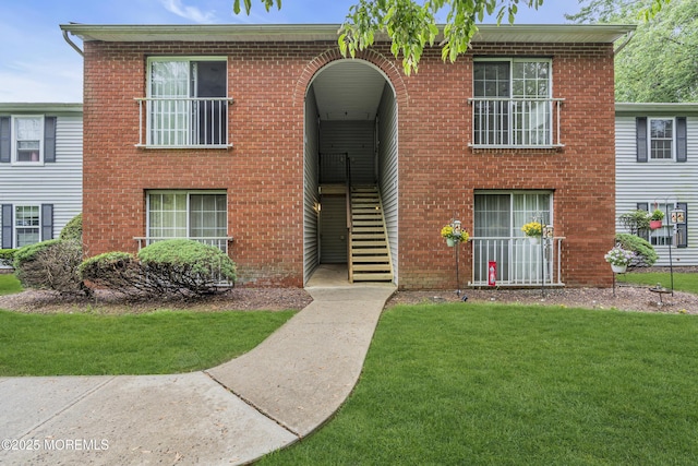 view of front of home with a front yard, stairway, and brick siding