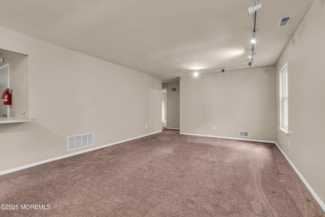 spare room featuring carpet flooring, track lighting, and baseboards