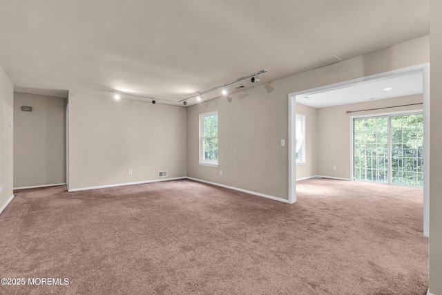 carpeted spare room featuring rail lighting and baseboards