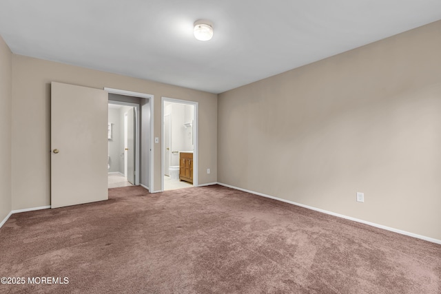 unfurnished bedroom with carpet floors, baseboards, and ensuite bathroom