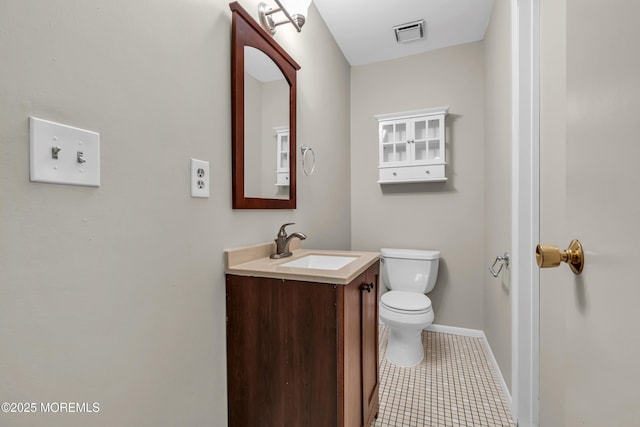 half bathroom with toilet, baseboards, vanity, and tile patterned floors