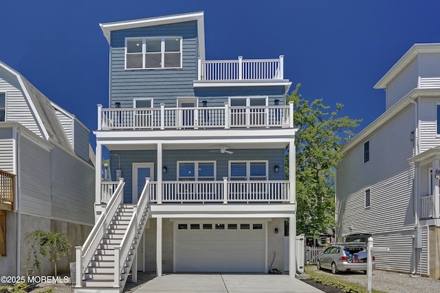 raised beach house with a balcony, driveway, a garage, covered porch, and stairway