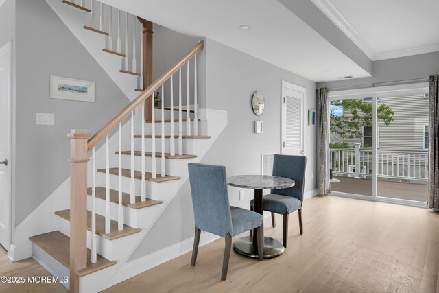 dining space featuring wood finished floors, ornamental molding, baseboards, and stairway