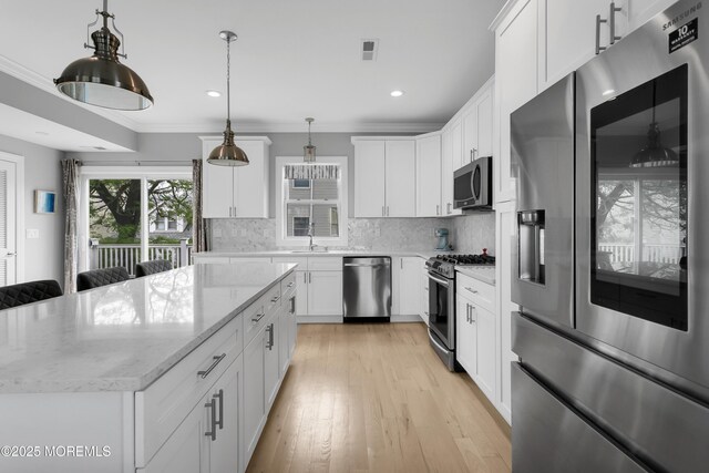 kitchen with appliances with stainless steel finishes, a sink, decorative backsplash, a center island, and white cabinets