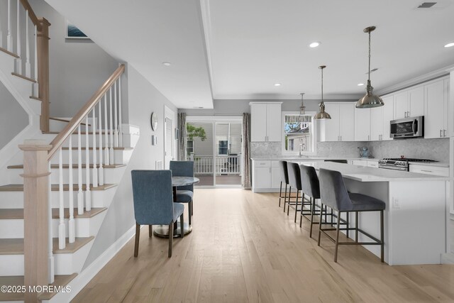 kitchen with stainless steel appliances, decorative backsplash, a kitchen bar, a kitchen island, and light wood-type flooring