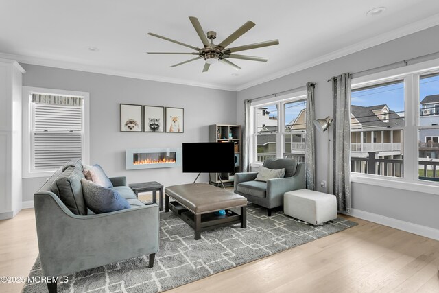 living area featuring wood finished floors, a ceiling fan, baseboards, and crown molding