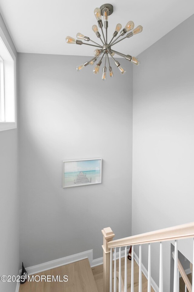 stairs featuring a chandelier, baseboards, and wood finished floors