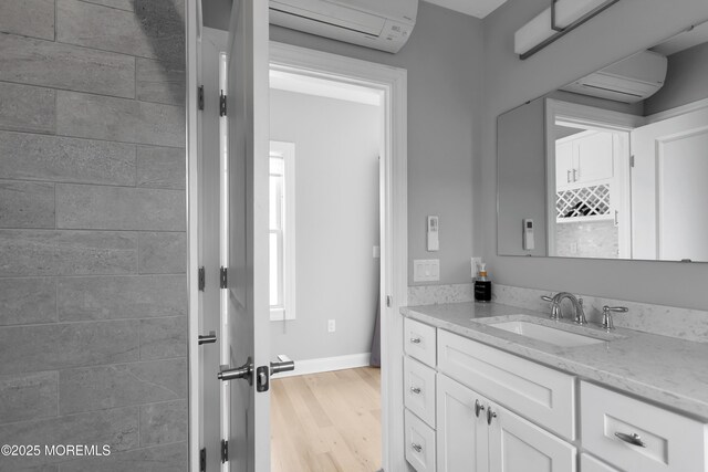bathroom with an AC wall unit, wood finished floors, vanity, and baseboards