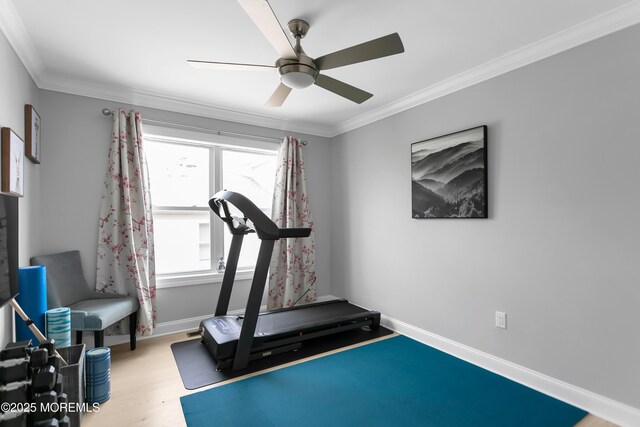 workout area with crown molding, a ceiling fan, wood finished floors, and baseboards