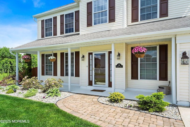 property entrance with covered porch and a shingled roof
