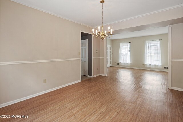 unfurnished room with a chandelier, baseboards, light wood-type flooring, and ornamental molding
