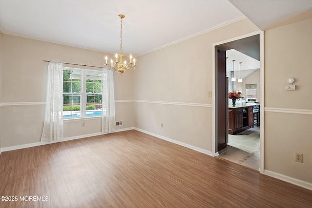 unfurnished room featuring light wood-type flooring, a chandelier, baseboards, and ornamental molding