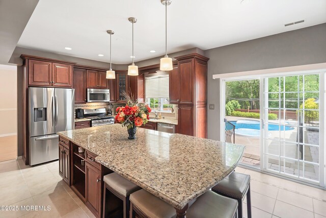 kitchen featuring stainless steel appliances, light tile patterned flooring, light stone counters, a breakfast bar area, and recessed lighting