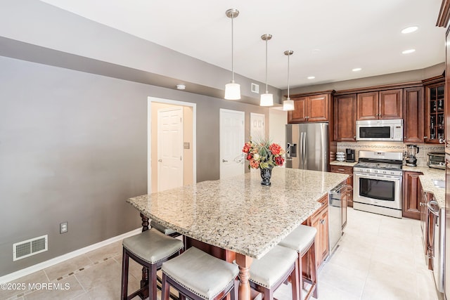 kitchen featuring stainless steel appliances, light tile patterned flooring, light stone counters, tasteful backsplash, and recessed lighting