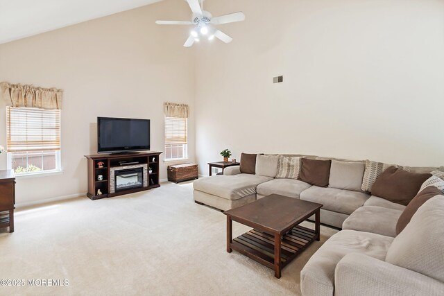 living room featuring high vaulted ceiling, light carpet, a ceiling fan, and baseboards