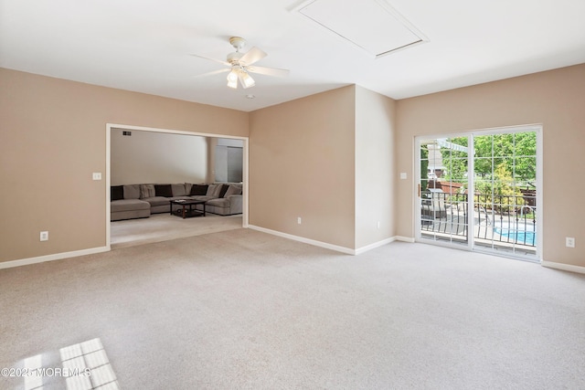 carpeted spare room featuring attic access, baseboards, and a ceiling fan