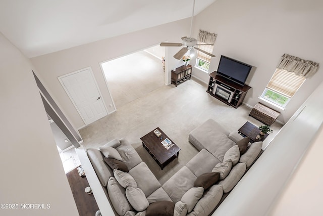 carpeted living room featuring ceiling fan and high vaulted ceiling