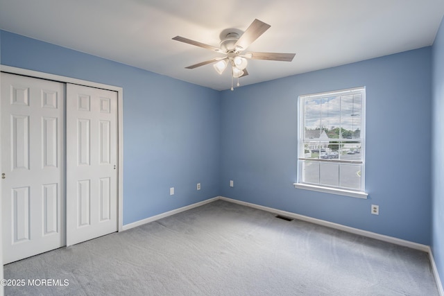 unfurnished bedroom featuring carpet, baseboards, a closet, and ceiling fan