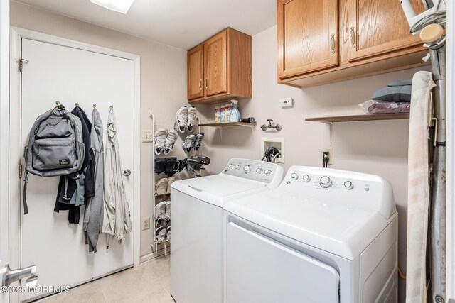 laundry room with washer and clothes dryer, cabinet space, and light tile patterned floors