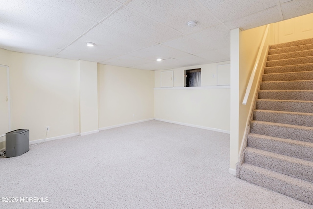 finished basement with stairs, a drop ceiling, baseboards, and carpet