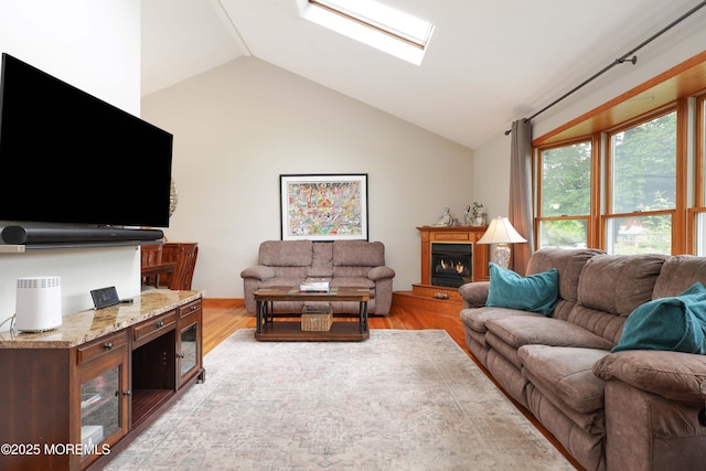2 Nassau Pl, Middletown, NJ 07748 - living area featuring vaulted ceiling, a skylight, light wood-style flooring, and a lit fireplace