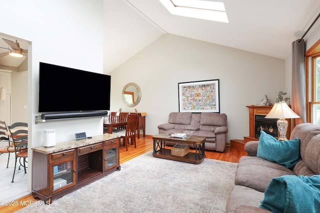 2 Nassau Pl, Middletown, NJ 07748 - living room with vaulted ceiling, a skylight, light wood-style floors, a ceiling fan, and a lit fireplace