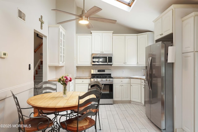2 Nassau Pl, Middletown, NJ 07748 - kitchen with appliances with stainless steel finishes, vaulted ceiling, a ceiling fan, a skylight, and backsplash