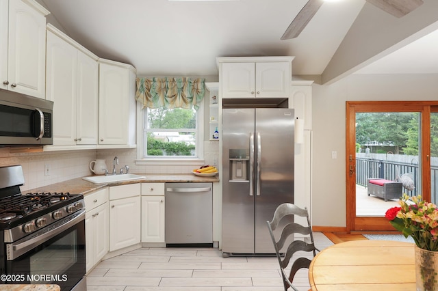 2 Nassau Pl, Middletown, NJ 07748 - kitchen featuring stainless steel appliances, decorative backsplash, a sink, white cabinets, and vaulted ceiling