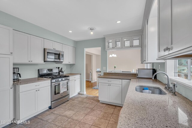 kitchen with appliances with stainless steel finishes, a sink, white cabinetry, recessed lighting, and light stone counters