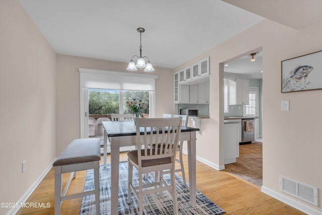 dining space featuring healthy amount of natural light, a chandelier, light wood finished floors, and baseboards